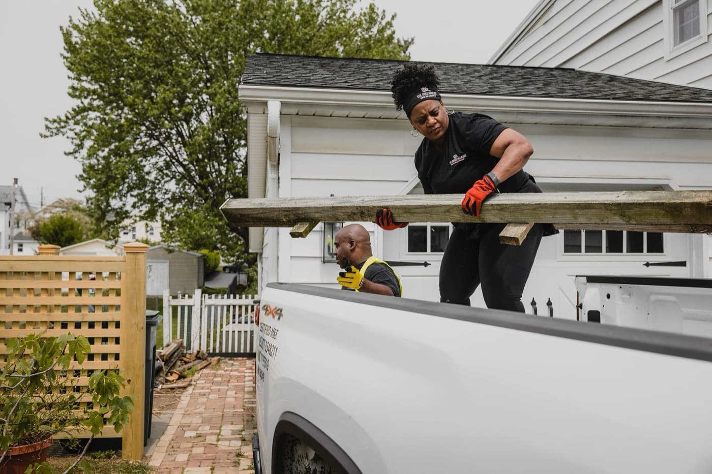 She Does Hauling founder and crew loading a wood beam into the branded company pickup