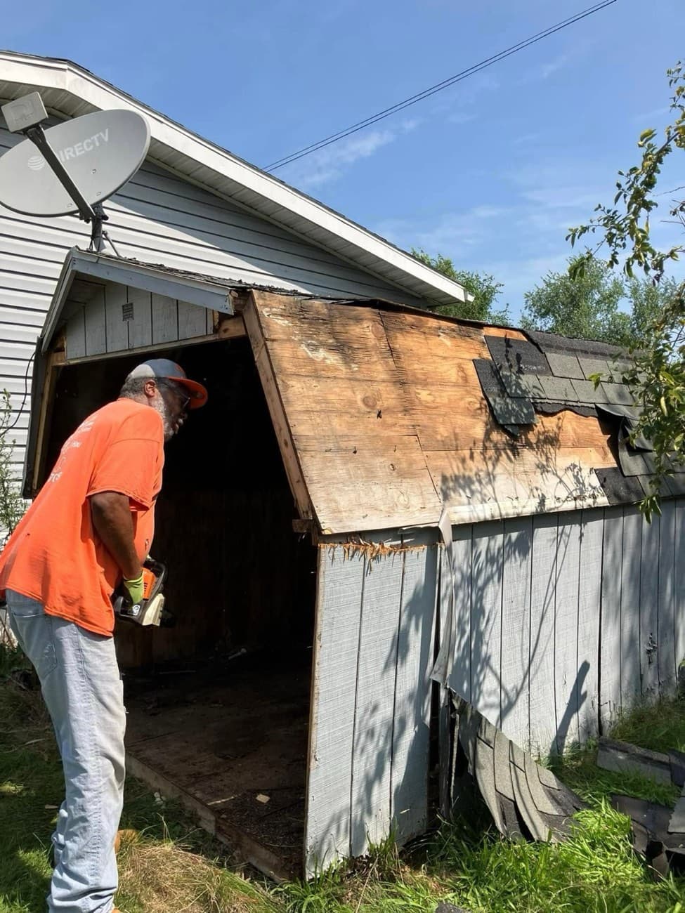 She Does Hauling crew member using a chainsaw to tear down a dilapidated shed